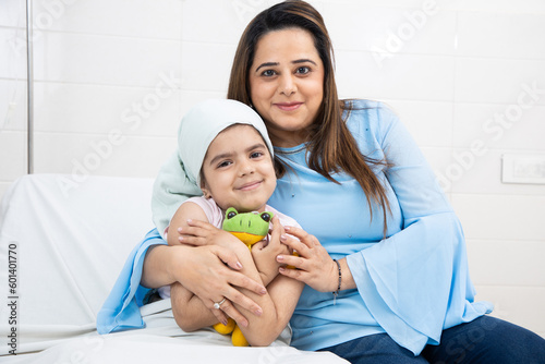 Indian woman hug her little daughter cancer patient undergoing course of chemotherapy in hospital looking at camera Fototapet