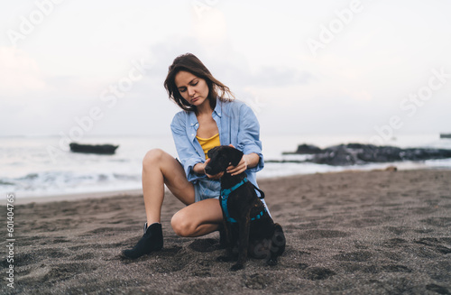 Calm woman sitting on sandy beach with dog