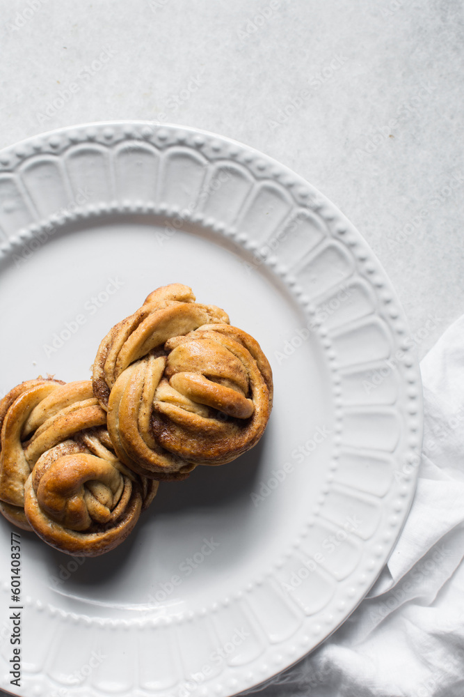 top view of Swedish cinnamon buns on a white plate, cinnamon twists on a plate, top view of homemade Kanelbullar top view of Swedish cinnamon buns on a white plate, cinnamon twists on a plate, top view of homemade Kanelbullar