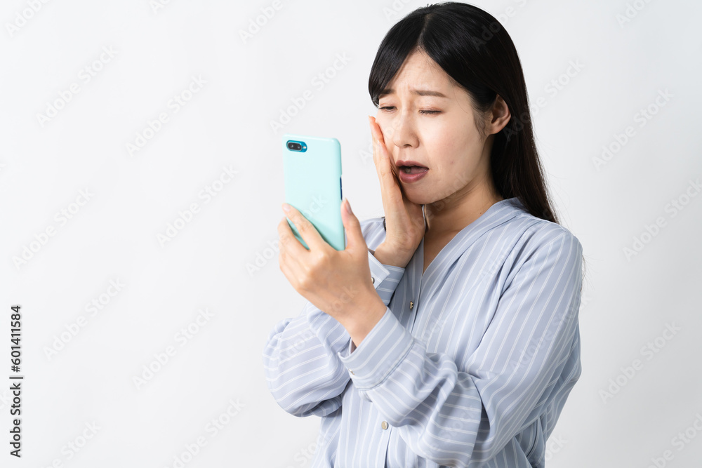 スマートフォンを持ちながらネガティブな表情をする若い女性 スマートフォンを持ちながらネガティブな表情をする若い女性