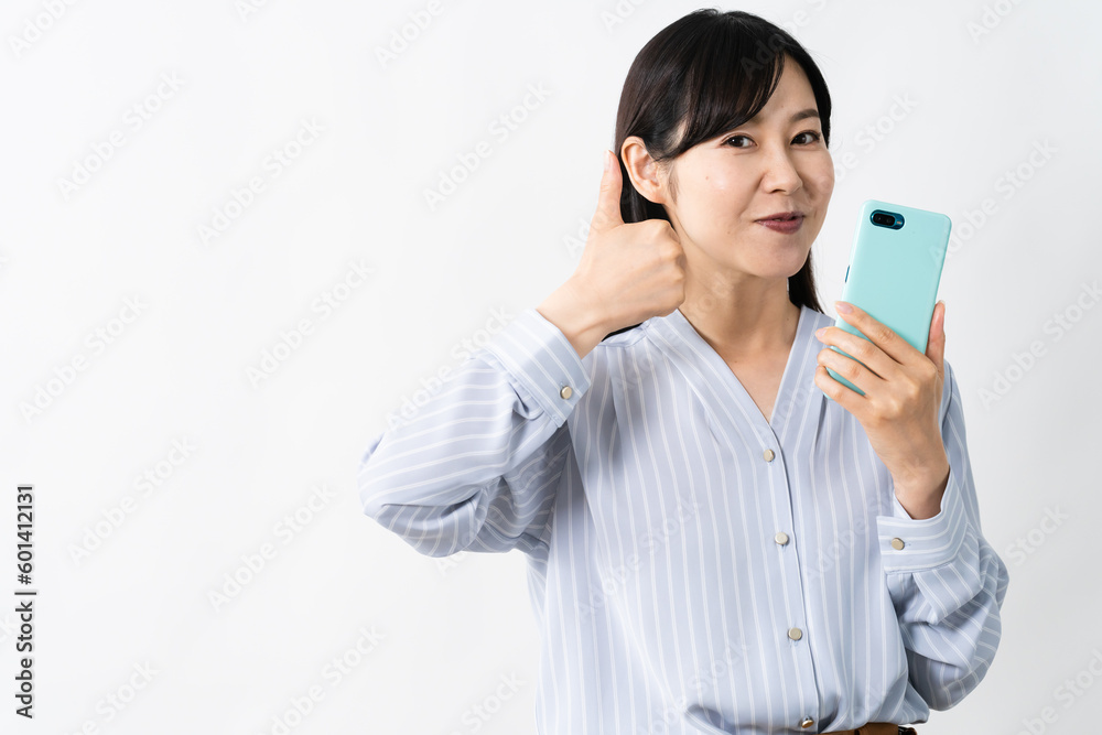 スマートフォンを持ちながらグッドサインをする若い女性 スマートフォンを持ちながらグッドサインをする若い女性