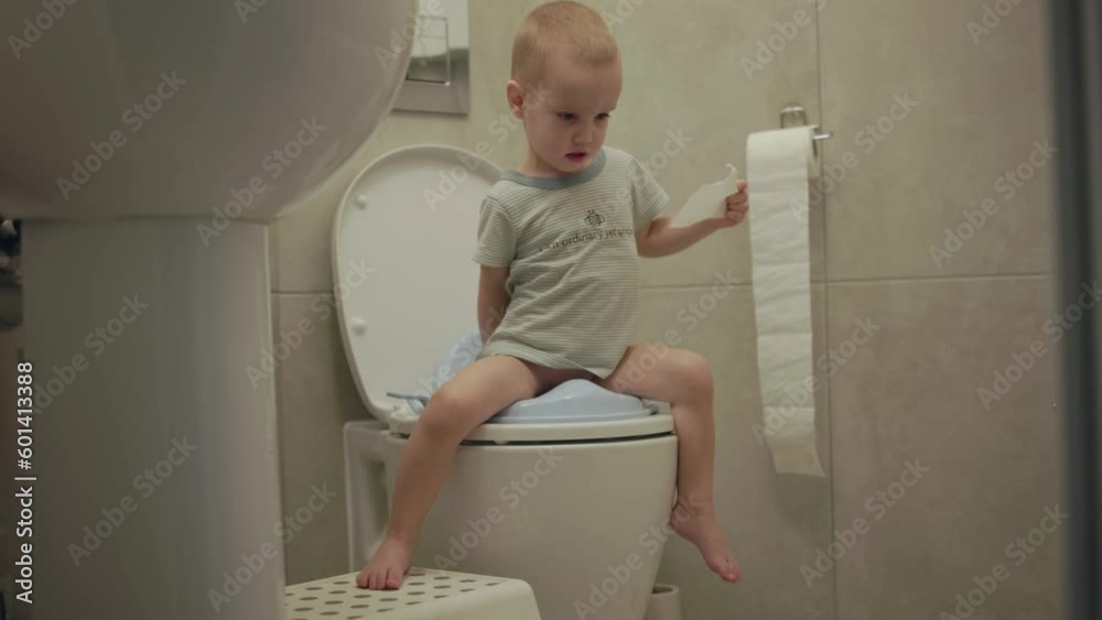 baby toddler sitting on toilet learning to clean his hygiene bottom