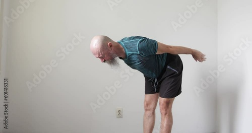 50 year old mid adult man with long beard doing neck and upper spine exercise at home, stretching hands forward and backwards, real people