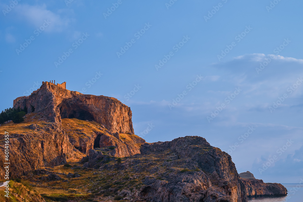 View of the acropolis of Lindos in early morning in rays of the rising sun, island of Rhodes, a famous place for recreation and travel around the islands of the Greek islands of Dodecanese archipelago