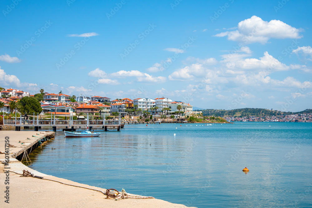 A promenade in Turkey, Ayvalik city. A boat and houses on the city's waterfront on a sunny summer day.