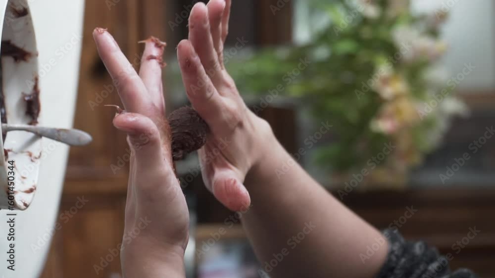 Vertical slow motion video of female hands rolling up brigadero chocolate, close up, natural light