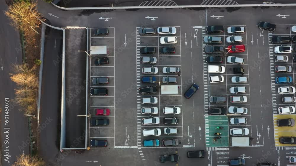 Aerial view of large parking lot in front shopping mall with many parked cars. Carpark at supermarket with lines and markings for vehicle places and directions Aerial view of large parking lot in front shopping mall with many parked cars. Carpark at supermarket with lines and markings for vehicle places and directions