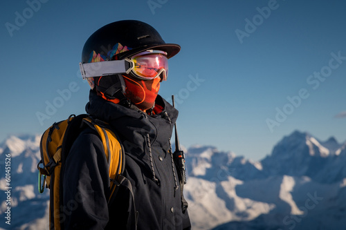 Profile of a female skier in ski goggles in the mountains. A woman in a sports ski jacket and snowboard sunglasses looks away. Sportswear and fashion for winter sports, ski resort