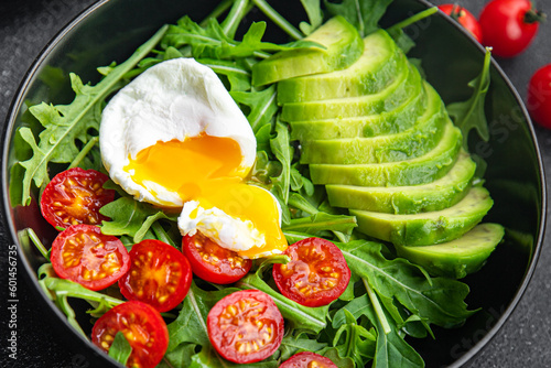 avocado salad poached egg, arugula, tomato, green salad leaves healthy meal food snack on the table copy space food background rustic top view keto or paleo diet veggie vegan or vegetarian food