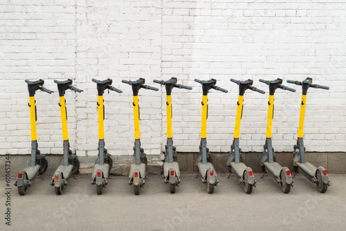 A lot of electric scooters against a white brick wall