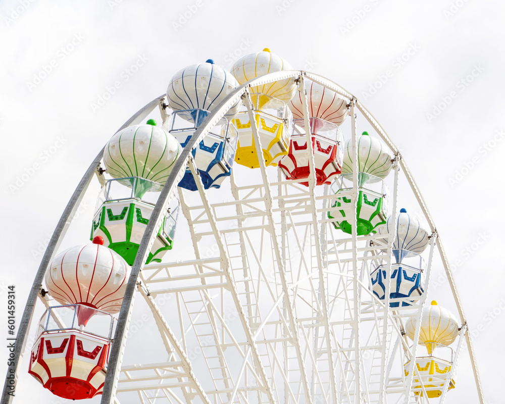 Fototapeta premium Ferris wheel in an amusement park. White design, multi-colored cabins.