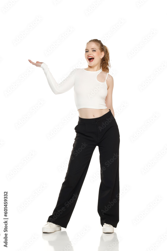 Young happy blonde woman with tied hair over isolated white background holding copyspace imaginary object on the palm to insert an ad Young happy blonde woman with tied hair over isolated white background holding copyspace imaginary object on the palm to insert an ad