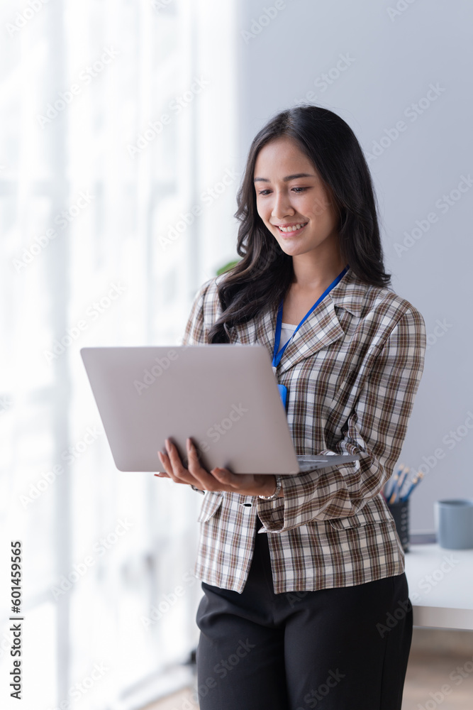 Young Asian businesswoman beautiful, charming smiling and using a laptop work in the office. Young Asian businesswoman beautiful, charming smiling and using a laptop work in the office.