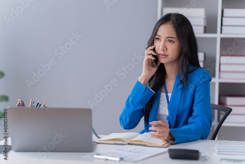  Asian Businesswoman Using laptop computer and working at office with calculator document on desk, using smartphone doing planning, business plan investment, finance analysis concept.