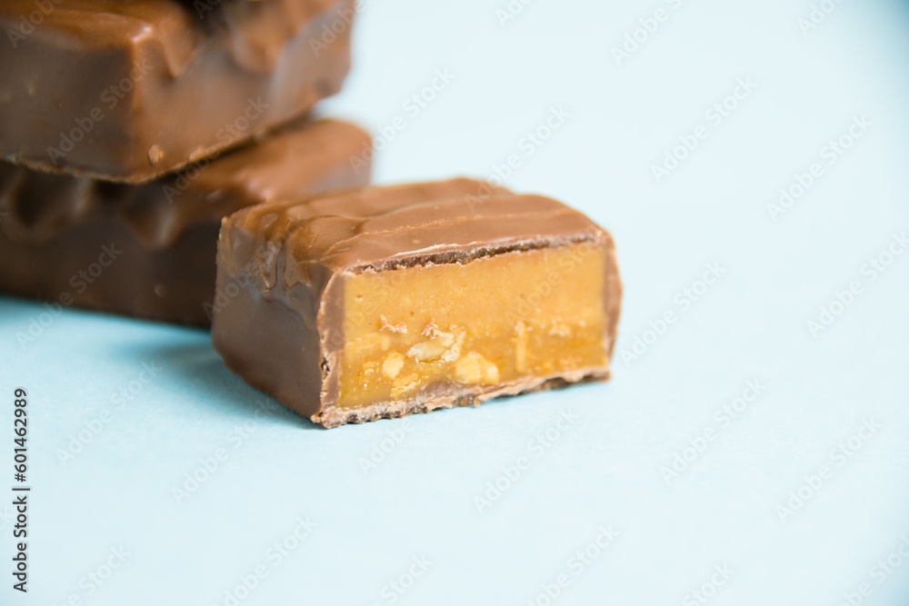 Delicious chocolate bars with salted caramel on a blue paper background Delicious chocolate bars with salted caramel on a blue paper background