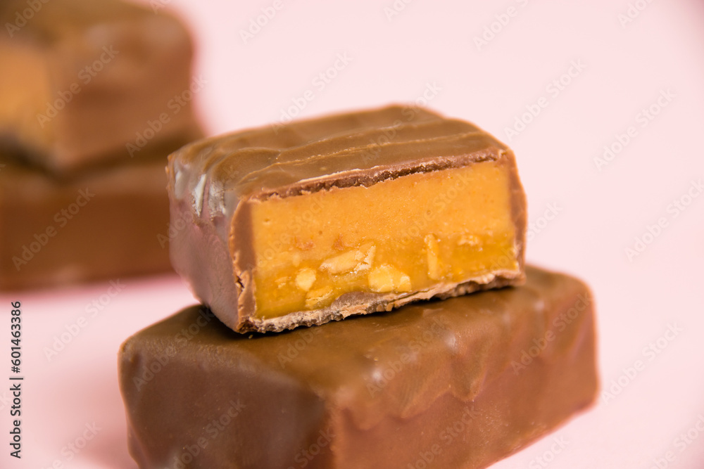 Sweet chocolate bar with salted caramel macro on pink paper background with copy space Sweet chocolate bar with salted caramel macro on pink paper background with copy space