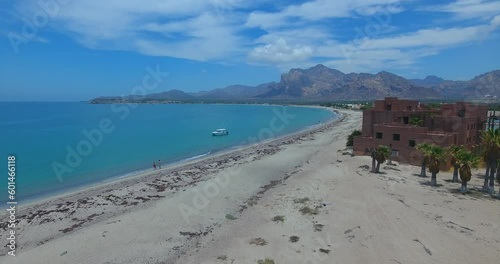 Forward Flight Near Lagoon and Palm Tree Resort with Persons Walking and Boat at Beach