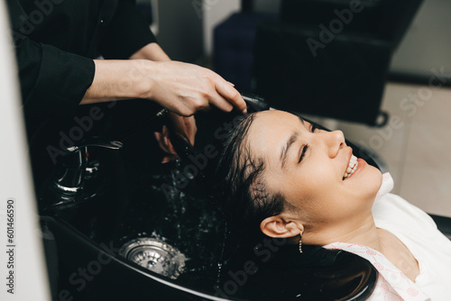 The hairdresser washes the head of a girl in a barbershop. brunette came for a haircut