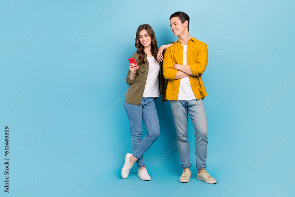 Full body length cadre of positive good mood couple choosing home decor website hold phone browsing ikea internet isolated on blue color background - obrazy, fototapety, plakaty 