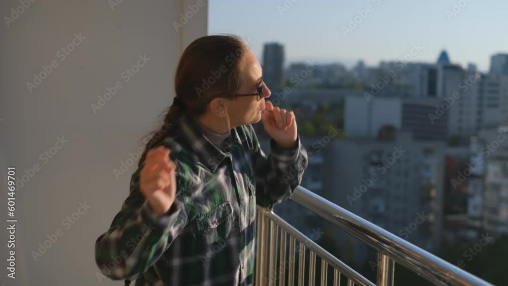 Cheerful adult mature woman dancing and having fun on the balcony alone Cheerful adult mature woman dancing and having fun on the balcony alone