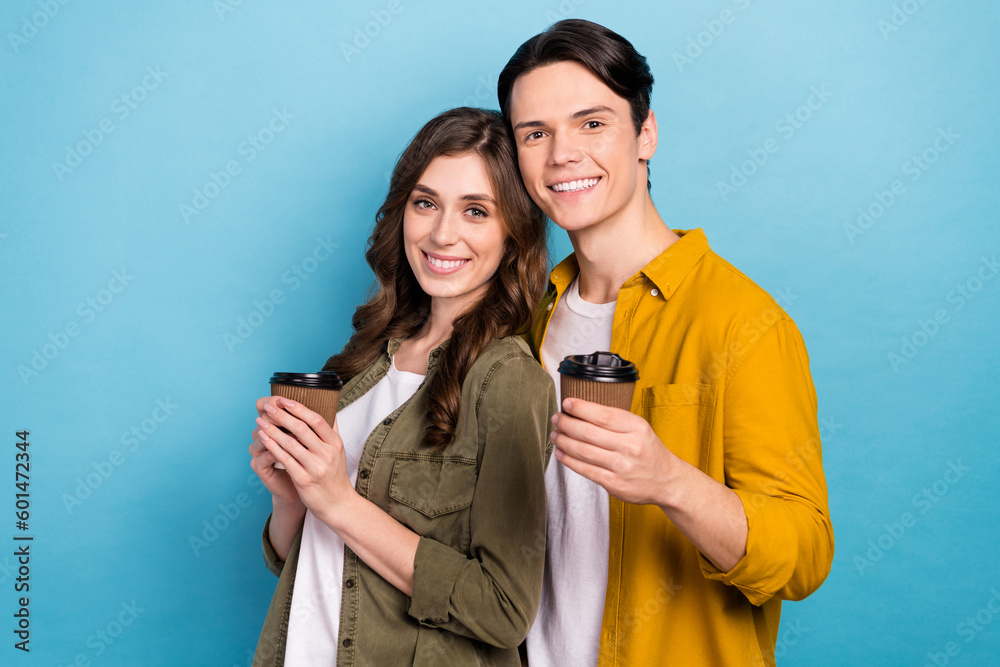 Portrait of cute love story couple drink hold their paper plastic cups with fresh coffee idyllic smiling energy isolated on blue color background Portrait of cute love story couple drink hold their paper plastic cups with fresh coffee idyllic smiling energy isolated on blue color background
