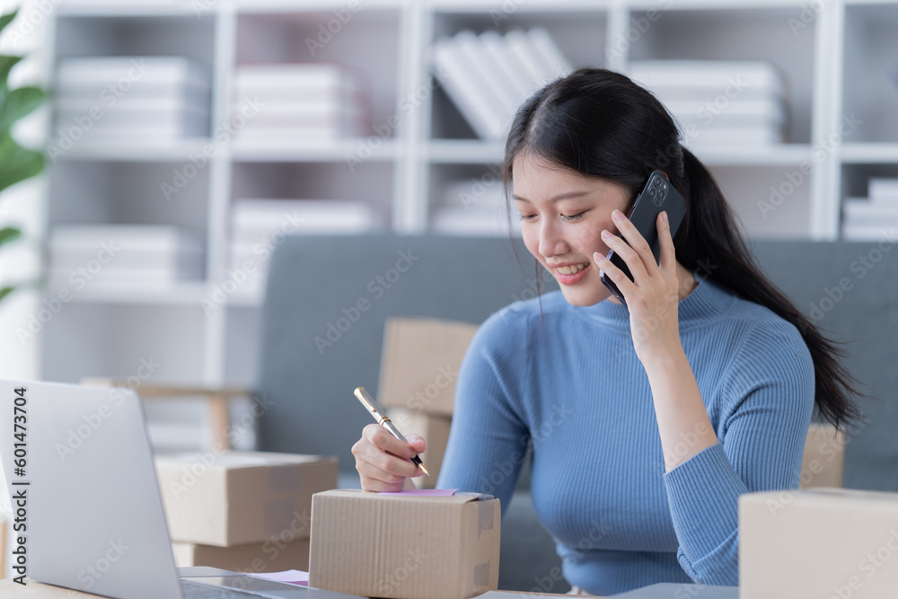 Startup SME small business entrepreneur of freelance Asian woman using a laptop with box Cheerful success Asian woman her hand lifts up online marketing packaging box and delivery SME 