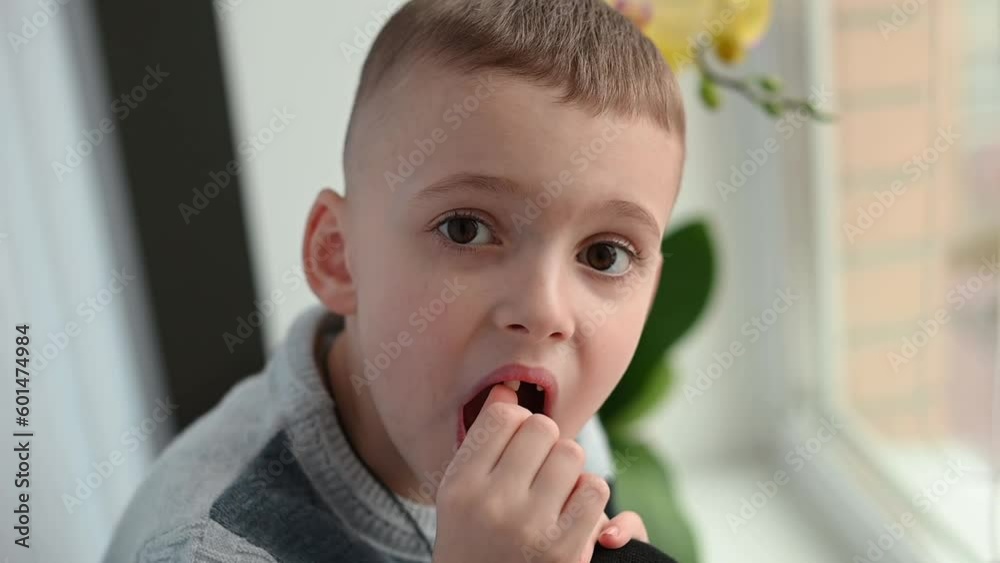 A brave little boy of 7 years old shakes his baby tooth. Change of teeth in children. Self-treatment at home. A brave little boy of 7 years old shakes his baby tooth. Change of teeth in children. Self-treatment at home.