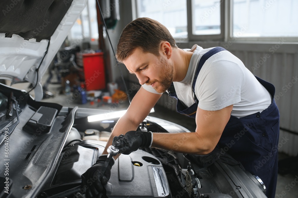 Portrait Shot of a Handsome Mechanic Working on a Vehicle in a Car Service. Modern Clean Workshop. Portrait Shot of a Handsome Mechanic Working on a Vehicle in a Car Service. Modern Clean Workshop.