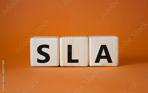 SLA - Service Level Agreement. Wooden cubes with word SLA. Beautiful orange background. Business and Service Level Agreement concept. Copy space.