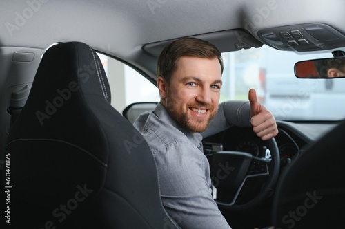 Taxi driver smiling while turning over to the backseat looking talking with clients. Successful businessman husband looking at the backseat at dealer shop before buying a car