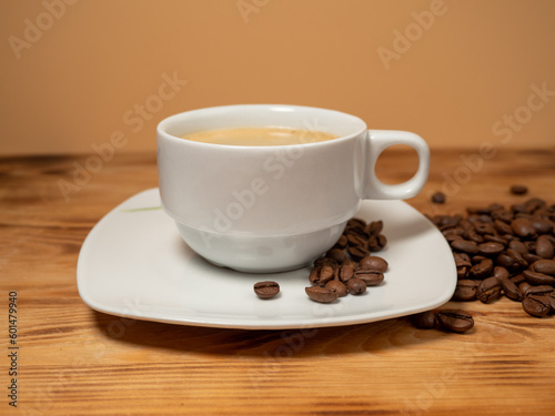 Cup of coffee and roasted coffee beans on a wooden background.