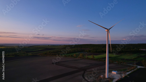Windmill turbines generating green energy electric at sunset.