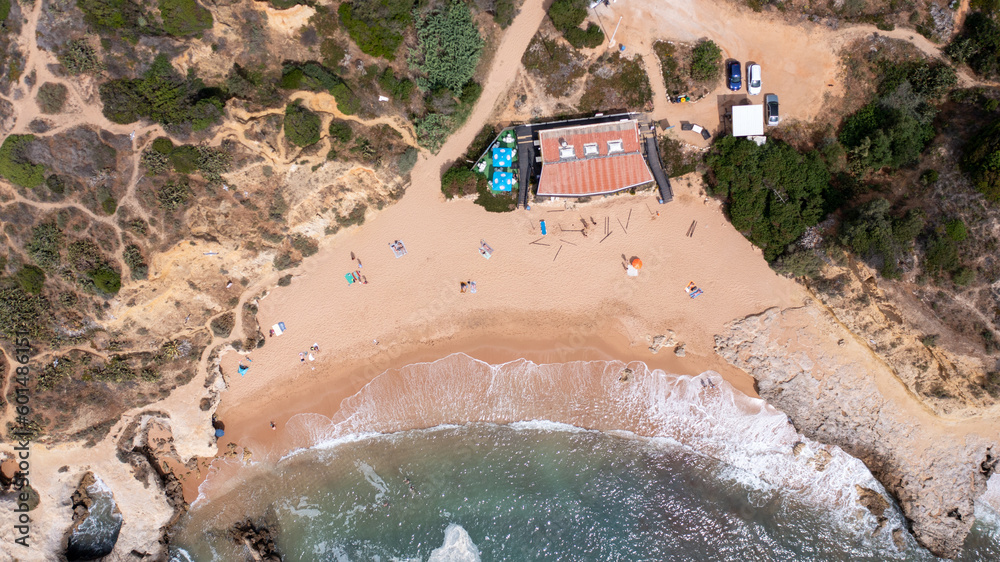 Straight down aerial photo of the beautiful town in Albufeira in Portugal showing the Praia dos Aveiros beach with and people relaxing on vacation on the beach on a hot summers day in the summer.