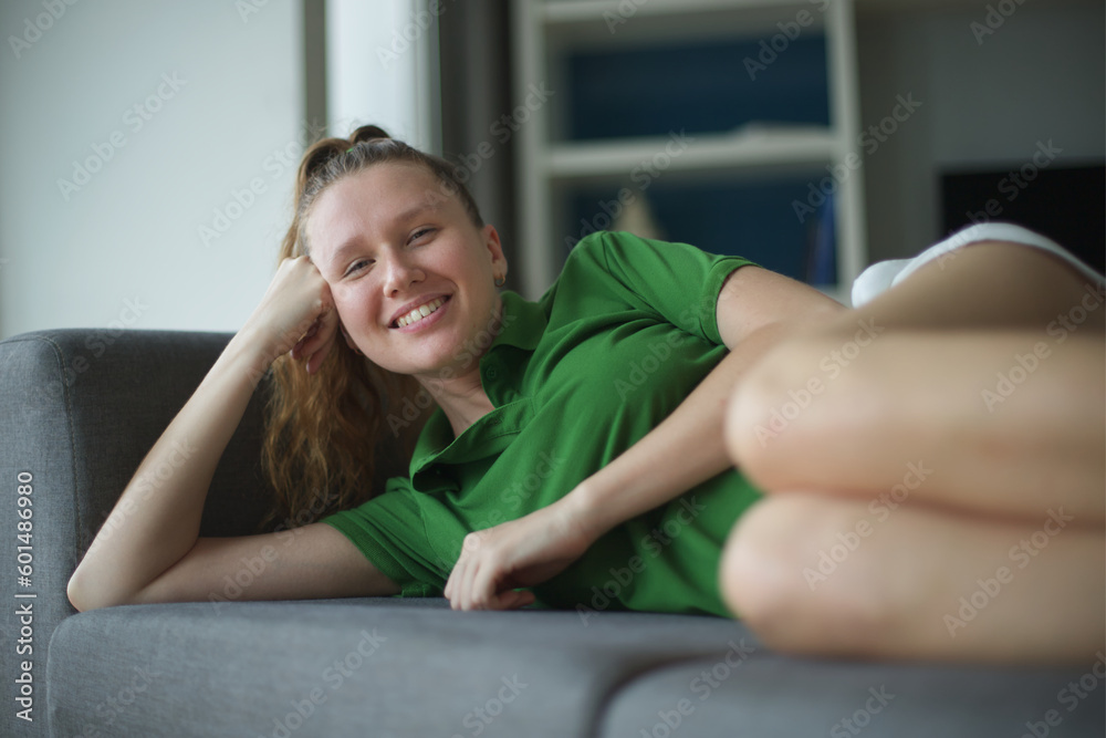 happy young woman sit on sofa and have a rest, relaxing living room at home in green polo t-shirt happy young woman sit on sofa and have a rest, relaxing living room at home in green polo t-shirt