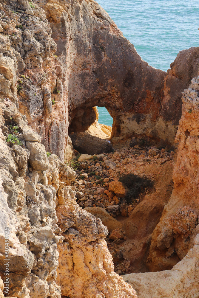 Hole in limestone rock next to the Atlantic Ocean on a sunny winter day in southern Portugal next to the Seven Hanging Valleys Trail.