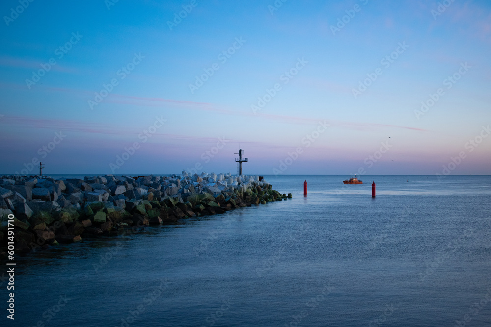 Obraz premium Sunset enveloping the blue sea and the beach