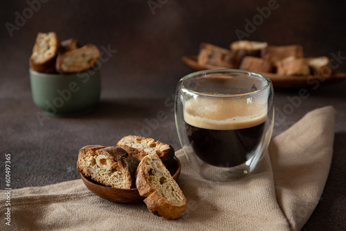 Italian biscotti with hazelnuts on wooden plate on dark brown blurred background 