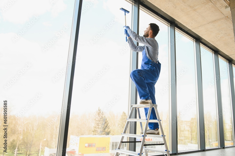 Young man cleaning window in office Young man cleaning window in office