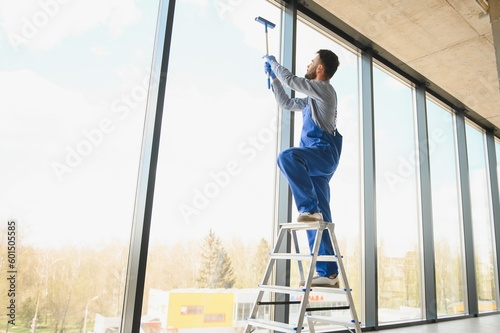 Young man cleaning window in office