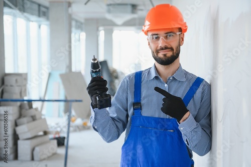 Portrait of young and hardworking constructor posing in big unfinished room. Building concept
