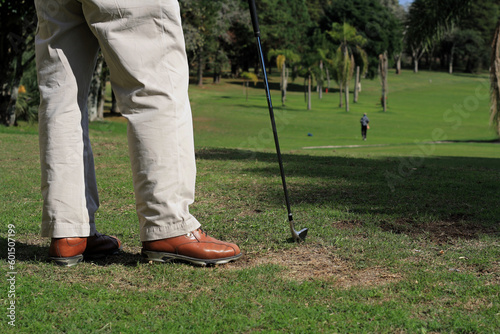 Homem com taco na mão a espera para dar a tacada em jogo de golf no gramado do club. photo