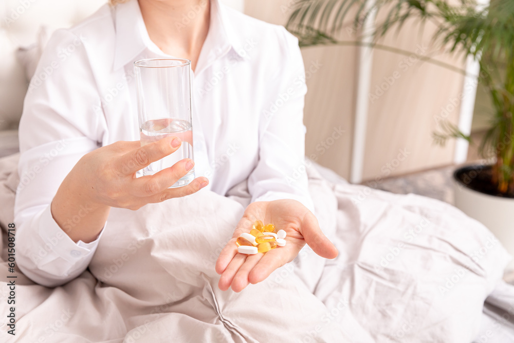 Close up woman holding tablets Omega-3 and glass of fresh water in the morning. Supplement, daily vitamins for hair and skin, natural beauty, healthy lifestyle Close up woman holding tablets Omega-3 and glass of fresh water in the morning. Supplement, daily vitamins for hair and skin, natural beauty, healthy lifestyle