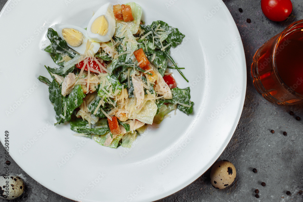 Traditional caesar salad in a white bowl on a old white table with leaves and a sauce boat and parmesan. Selected focus. Traditional caesar salad in a white bowl on a old white table with leaves and a sauce boat and parmesan. Selected focus.