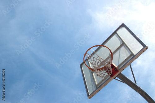 Outdoor neighborhood basketball court park and recreational area, Basketball net and backboard against sunny blue sky with copy space © Shawn C. Neill
