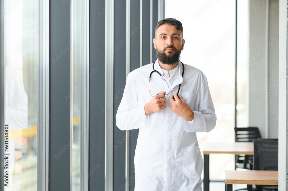 Portrait of pleasant young Arabian doctor in white coat.