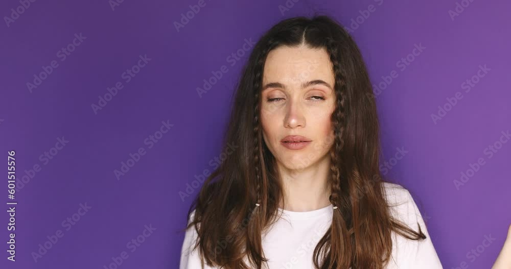 Displeased young woman showing nonsense gestures. Gossips indifference, isolated on purple studio background. Irritated brunette girl with braids showing bla blah gesture.