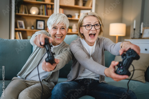 Two senior women caucasian friends or sisters play console video game