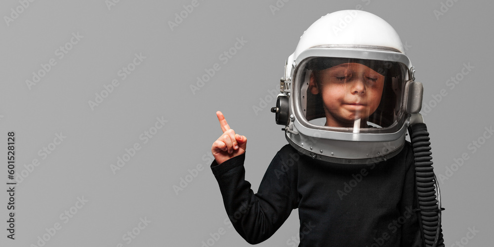 Small child wants to fly an in space wearing an astronaut helmet.