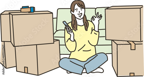 段ボールの前でスマホを持ちOKを出す女性
