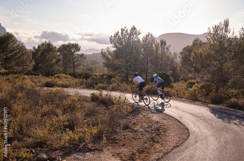 Men cyclists riding a gravel bicycles on the road in hills with mountain view, Alicante region in Spain.